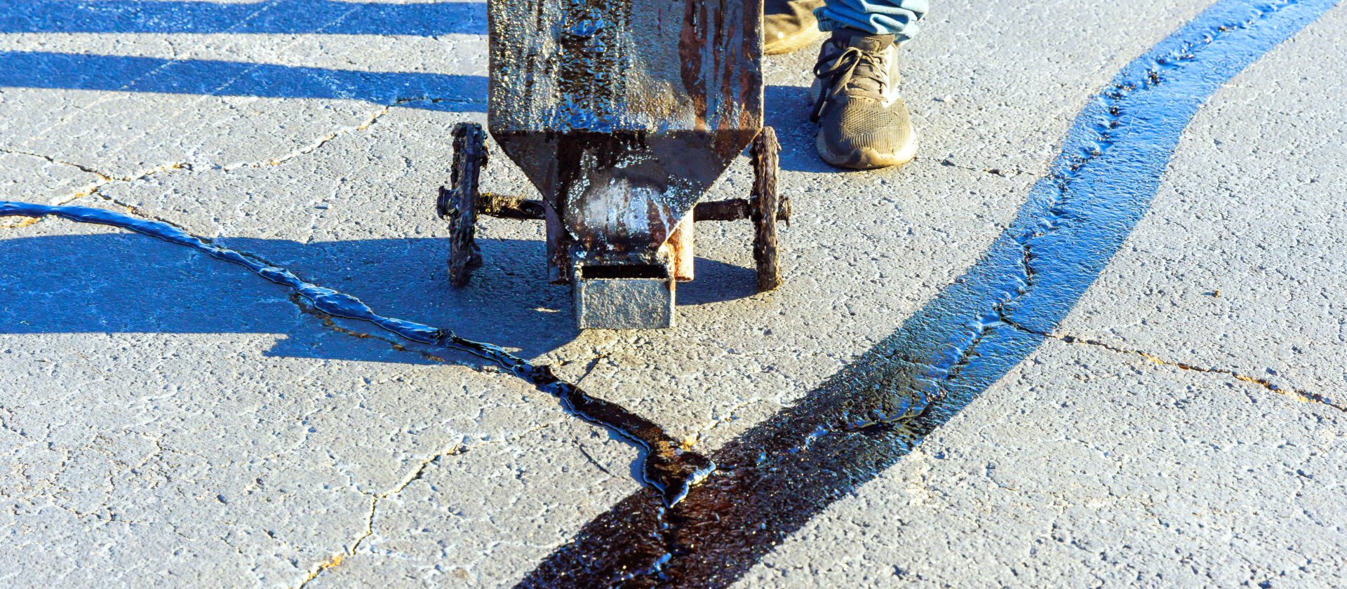 An asphalt patcher performs coated filling asphalt cracks sealing bitumen emulsion road
